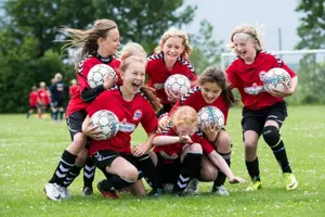 Group of girls from football team holding balls and laughing